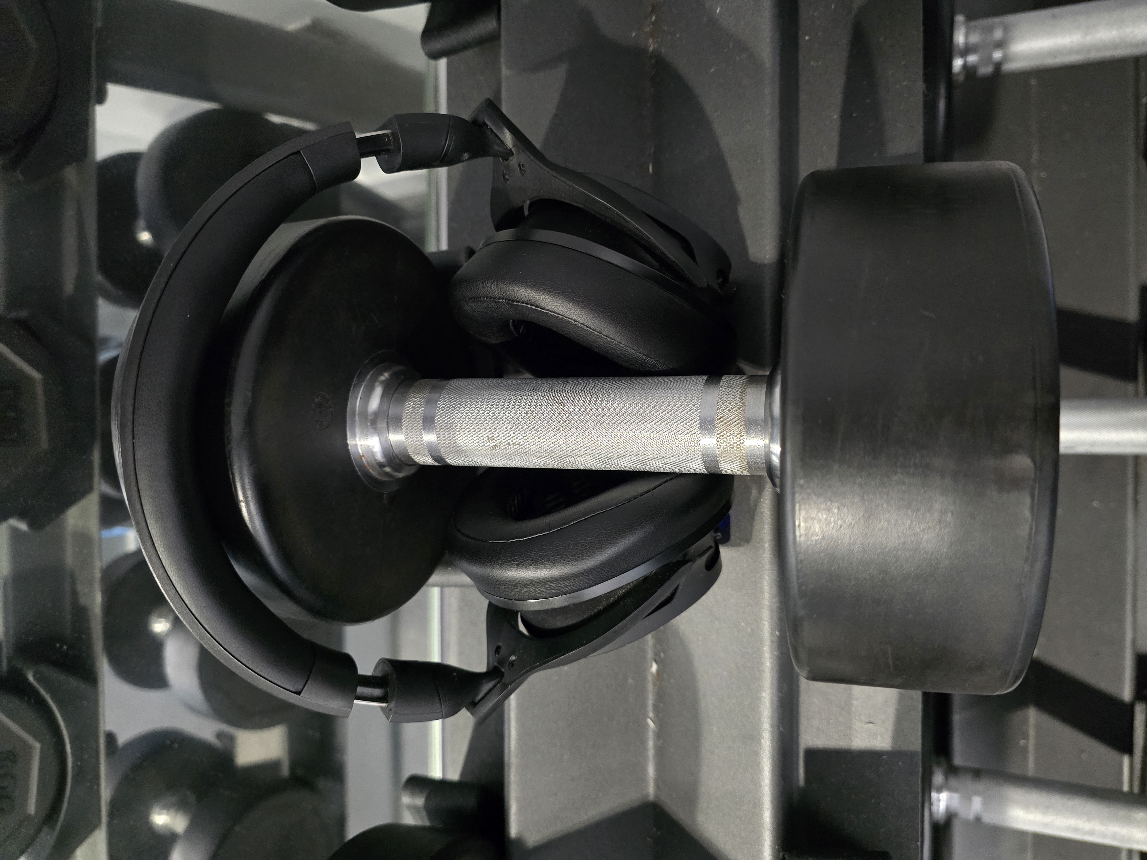Headphones surrounding a dumbbell on a weight rack