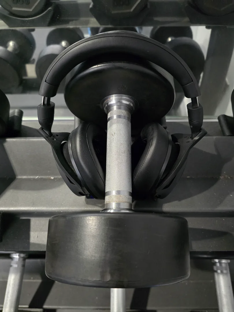 Headphones surrounding a dumbbell on a weight rack